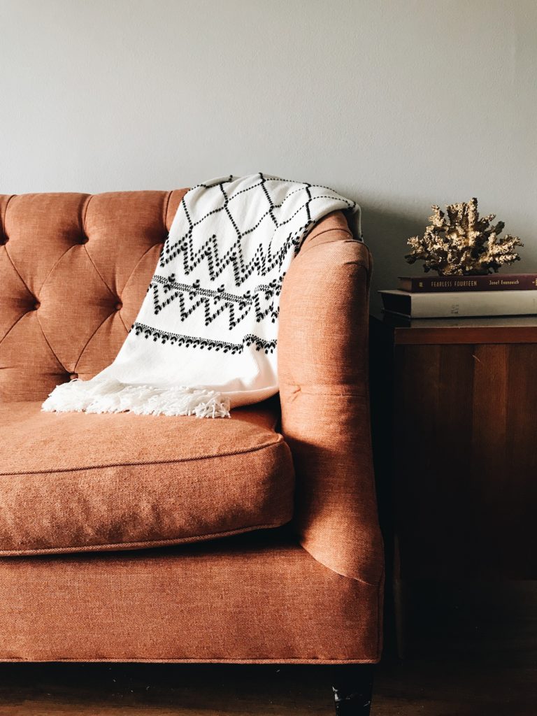Throw blanket over brown couch illustrating layering texture