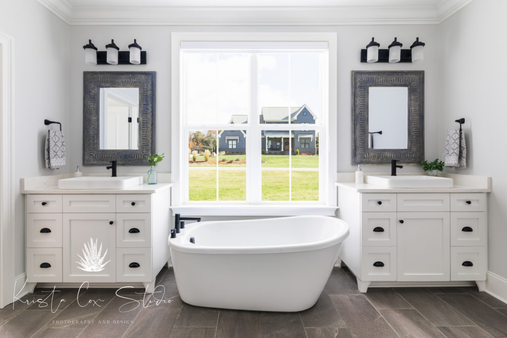 Interior photography of master bath featuring two vanities, a standalone tub, and gray tile.