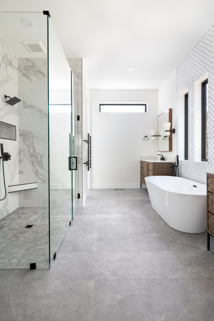 Primary bathroom with modern style featuring edgeless glass shower and standalone tub.